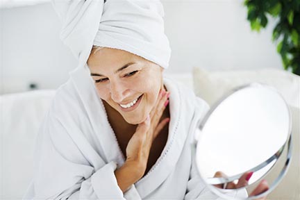 Woman in bathrobe after shower looking in the mirror