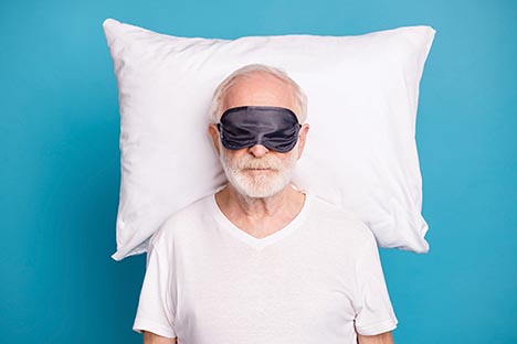 Man with head on pillow and eye-mask covering his eyes