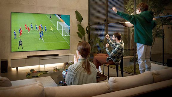 Family cheering for sports team on big screen TV